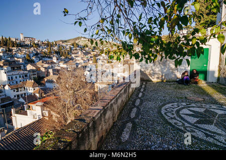 Zwei junge Frauen sitzen in La Churra square Aussichtspunkt an der Unesco Albaicin Altstadt suchen. Granada, Andalusien, Spanien Stockfoto