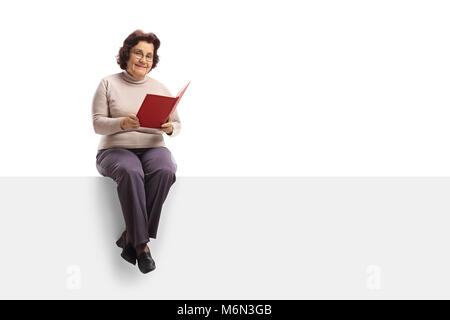 Ältere Frau mit einem Buch sitzen auf einem Panel auf weißem Hintergrund Stockfoto