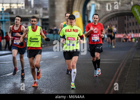 Der blinde Läufer Chris Goodwin und Reiseleiter laufen beim Vitality Big Halbmarathon über die Tower Bridge in London. T11 T12 Stockfoto