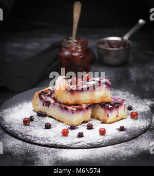 Kuchen aus Quark und Heidelbeeren auf schwarzem Hintergrund bestreut mit Puderzucker Stockfoto