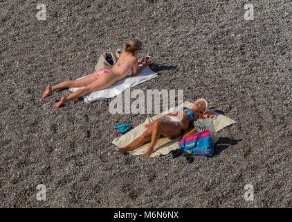 Junge Frau und alte Frau Sonnenbaden am Strand. Stockfoto