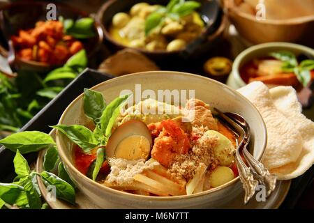 Lontong Cap klicken Sie meh. Die Javanese-Peranakan Reis Kuchen Suppe mit Hähnchen Curry, Chayote Squash Curry Soja, Ei, Garnelen Eintopf, Boden Soja- und Cracker. Stockfoto