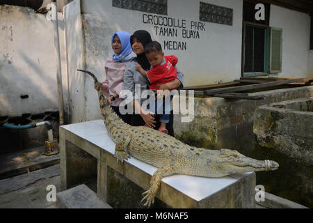 Medan, North Samatera, Indonesien. 9 Feb, 2018. Einheimische gesehen, ein Foto mit einem Krokodil. Der Käfer Krokodil Garten in Medan ist die größte Zucht in Gefangenschaft Zentrum von Krokodil Reptilien in Indonesien. Diese zwei Hektar großen Park liegt auch der größte Crocodile Park in Südostasien. Hier gibt es etwa 2800 Krokodile in verschiedenen Größen, darunter Krokodile, die über 40 Jahre alt sind. Diese Crocodile Park aus dem Hobby des Lo Tham Muk, ein Anwohner im Jahre 1959 entstand ein Reptil Tier sein. Jeden Tag dieses Krokodil ist Ente oder Huhn von den Besuchern gefüttert. (Bild: © Lanap Stockfoto