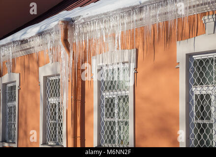 Lange Eiszapfen hängen von den Rand des Daches. Ende des Winters Stockfoto