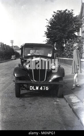 1947, historische, post-ww2 Großbritannien und ein junges Mädchen in Mantel wartet von einem Auto dieser Ära in einer Wohnstraße in sieben Könige, Ilford, Essex, England, UK geparkt. Stockfoto