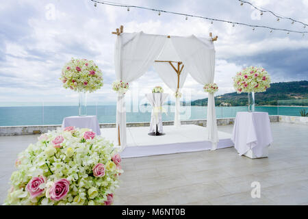 White Wedding Arch, Altar mit Rosen, Blumen, Blumen, Blumen, Ozean Hintergrund - Geschlossen Stockfoto