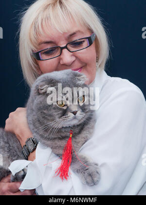 Portrait von Blonde reife Frau mit Brille holding Scottish Fold Katze Stockfoto