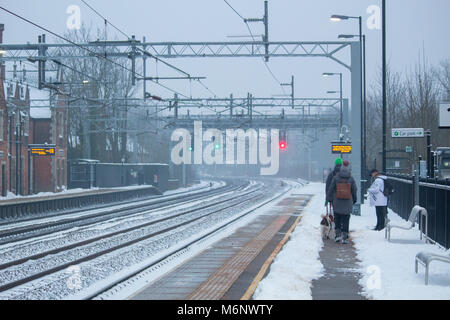 Passagiere warten auf einer Plattform an einem atherstone Bahnhof im Schnee bedeckt. Der Schnee wurde gelöscht ein Weg auf den Plattformen zu machen. Stockfoto