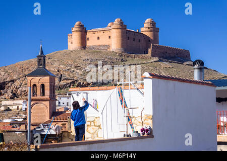 Schloss von La Herradura und ein junger Mann Wäsche aufhängen auf der Dachterrasse zu trocknen. La Calahorra, Provinz Granada, Andalusien, Spanien Stockfoto