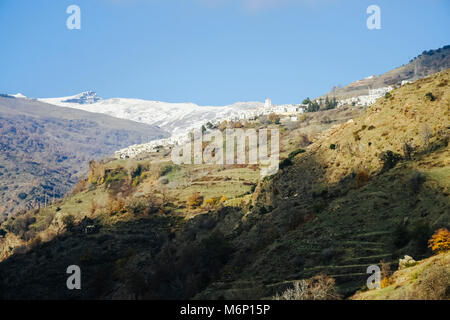 Blick auf die weiß getünchten Capileira Dorf mit schneebedeckten Gipfeln der Sierra Nevada im Hintergrund, im Las Alpujarras, Provinz Granada, Andalusien, Spanien Stockfoto