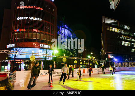 Junge Einheimische viel Spaß beim Skaten in der Nacht im Winter World Eisbahn am Potsdamer Platz, Berlin, Deutschland Stockfoto