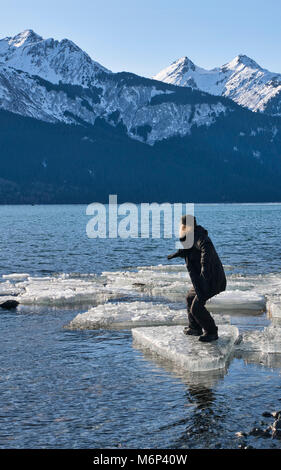 Mann auf einem Eisbrocken in einem surfen Position im Chilkat Einlass in Southeast Alaska im Winter. Stockfoto