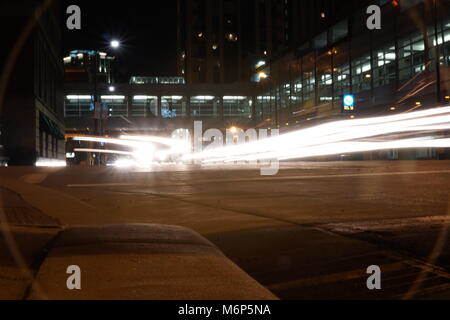 Leichte Wanderwege bei Nacht durch die Innenstadt von Minneapolis, Minnesota. Bremse und Scheinwerfer Streifen leuchtet, geschäftigen Stadt Straße Kreis lens flare viniette auf ca Stockfoto