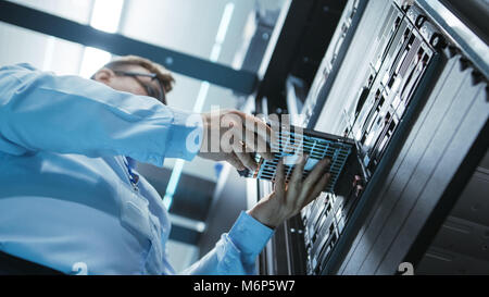 Lange Angle Shot in Voll funktionsfähige Rechenzentrum der IT-Techniker installieren Festplatte in Server Rack. Detaillierte und technisch präzise Aufnahmen. Stockfoto