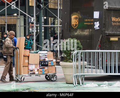 New York City - ca. 2017: UPS-Fahrer laden von Paketen auf einem Wagen aus der Rückseite des braunen Lkw auf Bestellungen und Boxen für Kunden in Manhattan liefern. Stockfoto