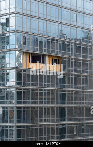 Zerbrochenes Glas klopfte aus Hochhaus Gebäude Fassade in der Stadt. Ply Holz Bretter Block außerhalb Wetter bis Glas durch den Bau der Instandsetzung behoben ist Stockfoto