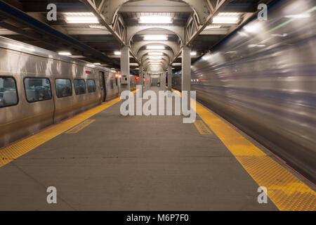 Lange Belichtung von high speed Zug passiert Bahnsteig warten, Abfahrt am Bahnhof Railroad Terminal Nabe Stockfoto