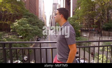 Jungen attraktiven Mann mit Brille lässig hinter New York City street. Tagsüber Blick hinunter 42. von der Straße Überführung Stockfoto