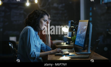 Gestresst, Überarbeitet weiblichen Finanzier hält Ihren Kopf in die Hände während der Arbeit auf einem PC. Im Hintergrund kreative Büro. Stockfoto