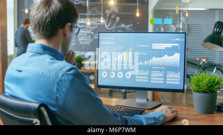 Finanzier arbeitet auf einem Personal Computer, Statistiken, Grafiken und Diagramme. Im Hintergrund seiner Mitarbeiter und Kreative Büro. Stockfoto