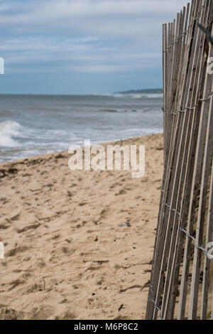 Küste Strand Blick hinter einem hölzernen Lattenzaun als Ozean Wellen am Ufer im Hintergrund Stockfoto