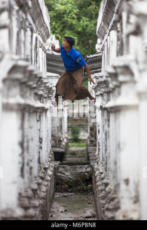 Ein junger Mann klettern die Weißen stupas Der Sandamuni Pagode in Mandalay, Myanmar (Birma). Stockfoto