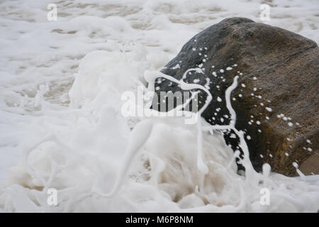 Ozean Wellen am Strand Ufer rock Schaum über Sand zu erstellen. Stockfoto