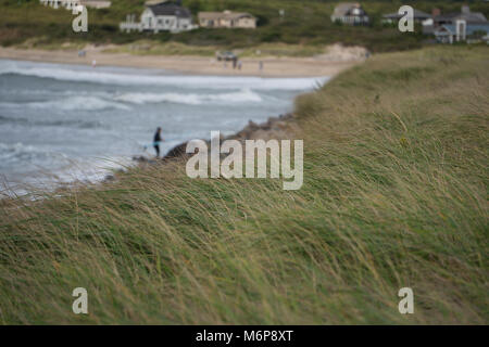Schöne Aussicht mit Blick auf Sand dune Grass am Strand Küste mit luxuriösen Sommerhäuser und Surfer in der Ferne Hintergrund Stockfoto