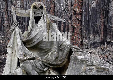 Sensenmann Statue mit Wald im Hintergrund durch Feuer zerstört Stockfoto