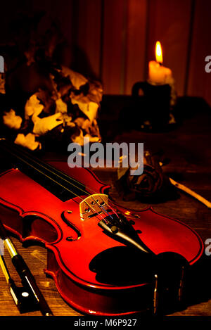 Violine, brennende Kerze und Blätter im Herbst auf dem Tisch Stockfoto
