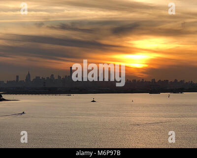 Majestätischen Sonnenuntergang Luftaufnahme orange sky Umgebung hinter dem Manhattan NYC Skyline über den Hafen Wasser Stockfoto