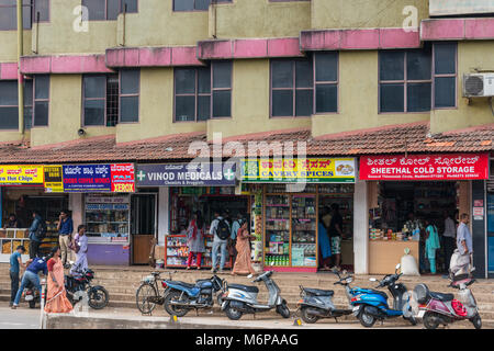 Madikeri, Indien - 31. Oktober 2013: Reihe von fünf Stores mit bunten billboars im Erdgeschoss des Wohnhauses. Street Scene mit Motor Stockfoto