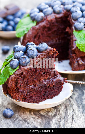 Schokoladenkuchen mit Schokolade und Sahne frische Blaubeeren und Minzeblättchen Stockfoto