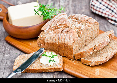 Scheiben Irischen stoneground Soda Brot mit Butter und Thymian auf dem hölzernen Tisch Stockfoto