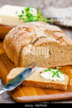 Scheiben Irischen stoneground Soda Brot mit Butter und Thymian auf dem hölzernen Tisch Stockfoto