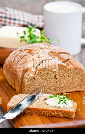 Scheiben Irischen stoneground Soda Brot mit Butter und Thymian auf dem hölzernen Tisch Stockfoto