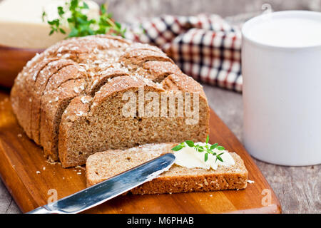 Scheiben Irischen stoneground Soda Brot mit Butter und Thymian auf dem hölzernen Tisch Stockfoto