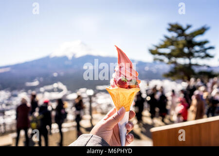 Matcha grüner Tee mit Milch und Erdbeer Eis Konus auf der Hand Stockfoto