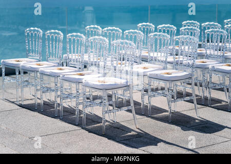 Ghost Stühle Line-up für Hochzeit, Sonne Licht Reflexion auf das Meer Stockfoto