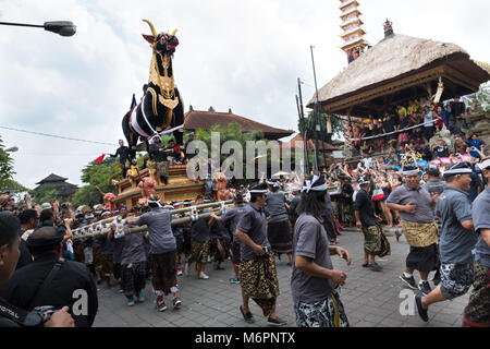 Balinesische Männer tragen die schwere schwarze Sarkophag Stier durch die Straßen von Ubud, Bali für die einäscherung Zeremonie der Königin Niang Agung Stockfoto