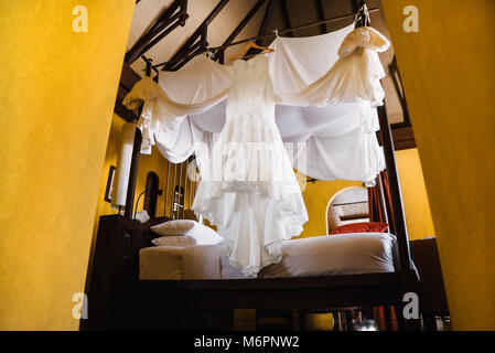 Die Hochzeit Kleid der Braut hängen auf dem Bett, Luxus, herrliches Kleid, das Zimmer mit gelben vintage Thema. Stockfoto