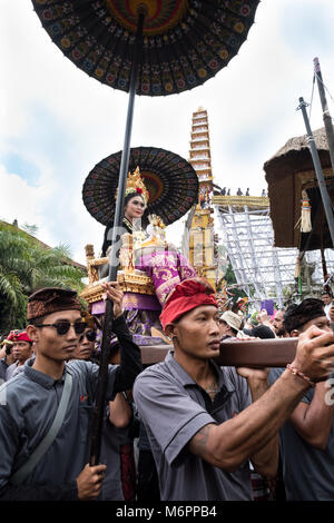 Balinesische Frauen in traditioneller Kleidung gekleidet und trägt eine goldene Kopfschmuck auf einem Wagen in den Tempel getragen für eine königliche Zeremonie, die Einäscherung Stockfoto