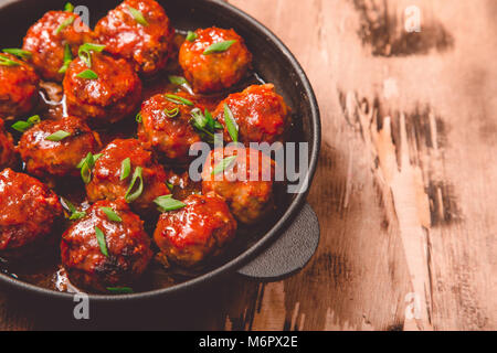 Fleischbällchen in süß-saurer Tomatensauce. Hausgemachte gebratenem Rindfleisch Fleischbällchen in Gusseisen Skillet. Stockfoto