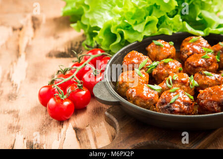 Fleischbällchen in süß-saurer Tomatensauce. Hausgemachte gebratenem Rindfleisch Fleischbällchen in Gusseisen Skillet. Stockfoto