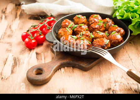 Fleischbällchen in süß-saurer Tomatensauce. Hausgemachte gebratenem Rindfleisch Fleischbällchen in Gusseisen Skillet. Stockfoto