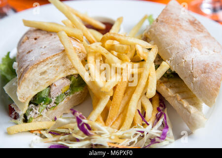 Sandwich mit Schinken, Käse und golden Pommes frites Kartoffeln auf einem weißen Teller. Stockfoto