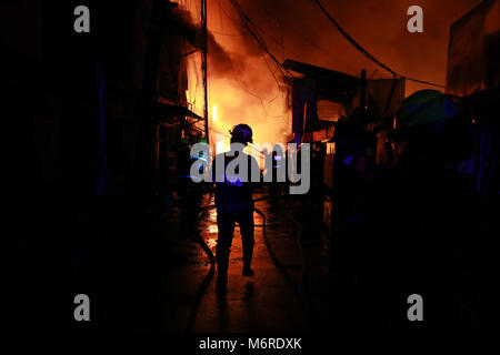 Quezon City, Philippinen. 6 Mär, 2018. Feuerwehr Brand in einem Slum in Quezon City, Philippinen, 6. März 2018 zu löschen. Credit: rouelle Umali/Xinhua/Alamy leben Nachrichten Stockfoto