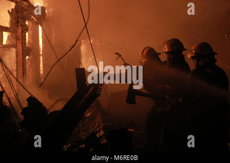 Quezon City, Philippinen. 6 Mär, 2018. Feuerwehr Brand in einem Slum in Quezon City, Philippinen, 6. März 2018 zu löschen. Credit: rouelle Umali/Xinhua/Alamy leben Nachrichten Stockfoto