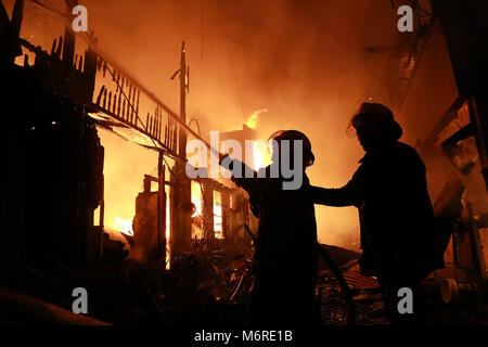 Quezon City, Philippinen. 6 Mär, 2018. Feuerwehr Brand in einem Slum in Quezon City, Philippinen, 6. März 2018 zu löschen. Credit: rouelle Umali/Xinhua/Alamy leben Nachrichten Stockfoto