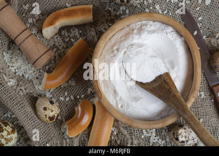 Reis Mehl in eine olivenholz Platte auf einem Sack. Stockfoto